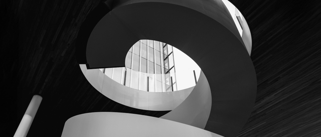 Una elegante escalera en espiral iluminada por luz natural en un entorno moderno.