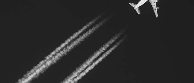 Un avión vuela en el cielo dejando estelas de condensación.