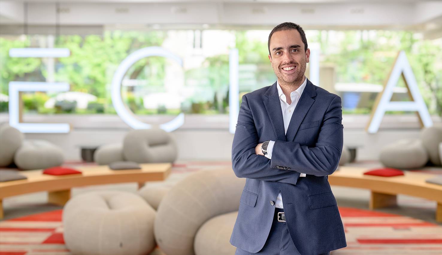 Un hombre sonriente en un entorno moderno y acogedor con muebles suaves.