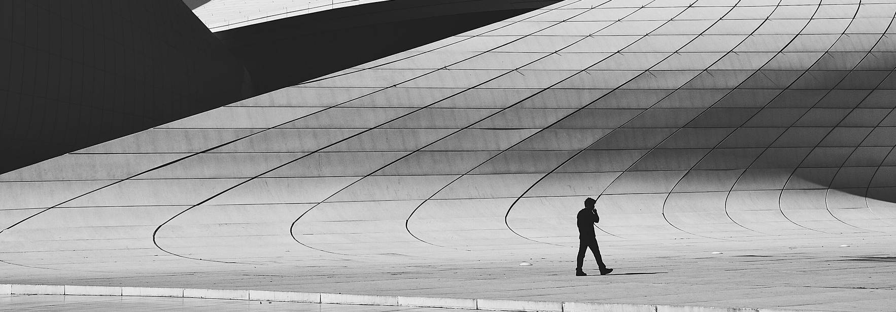 Una persona camina sola sobre una estructura arquitectónica de curvas sinuosas y formas modernas.