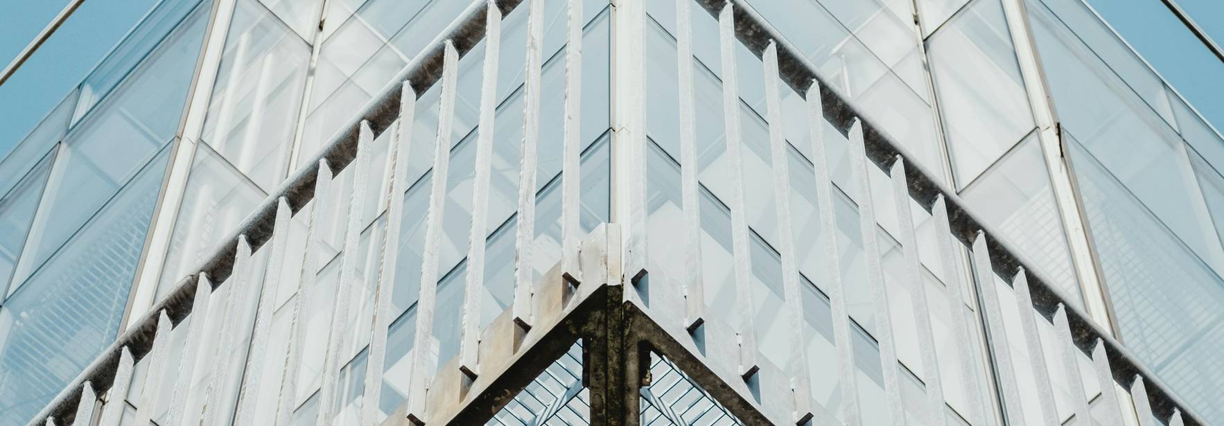 Una imagen del ángulo superior de un edificio moderno con estructuras de acero y paneles transparentes bajo un cielo despejado.
