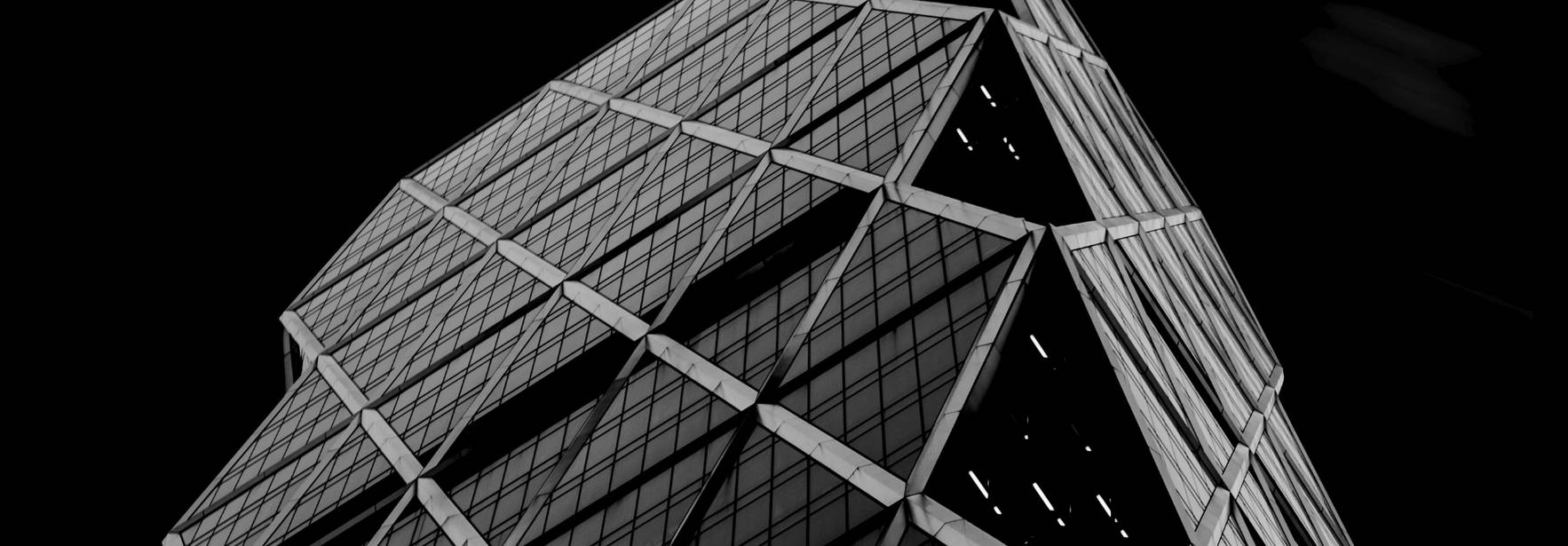 Una imagen de un rascacielos moderno visto desde abajo, destacando su diseño arquitectónico en blanco y negro.