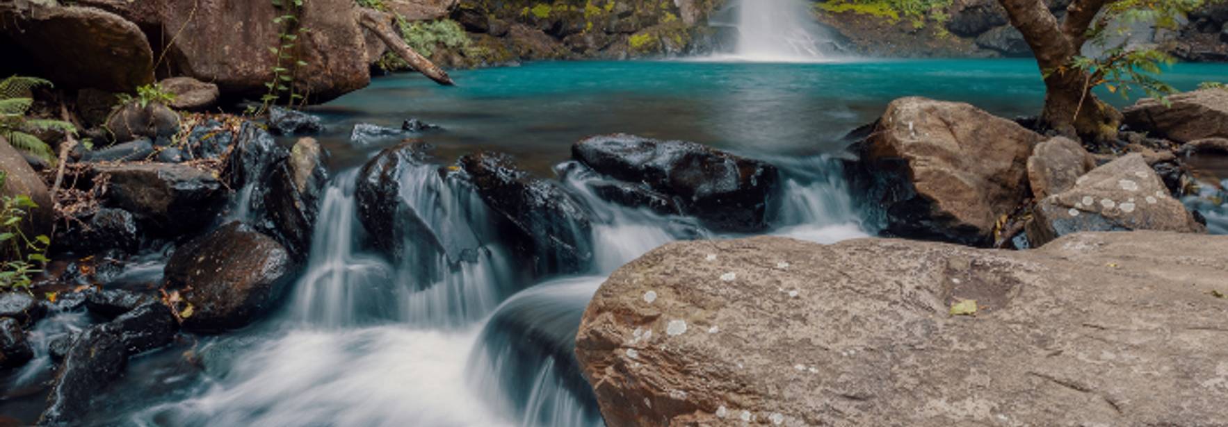 Una hermosa cascada rodeada de rocas y vegetación en un entorno natural.