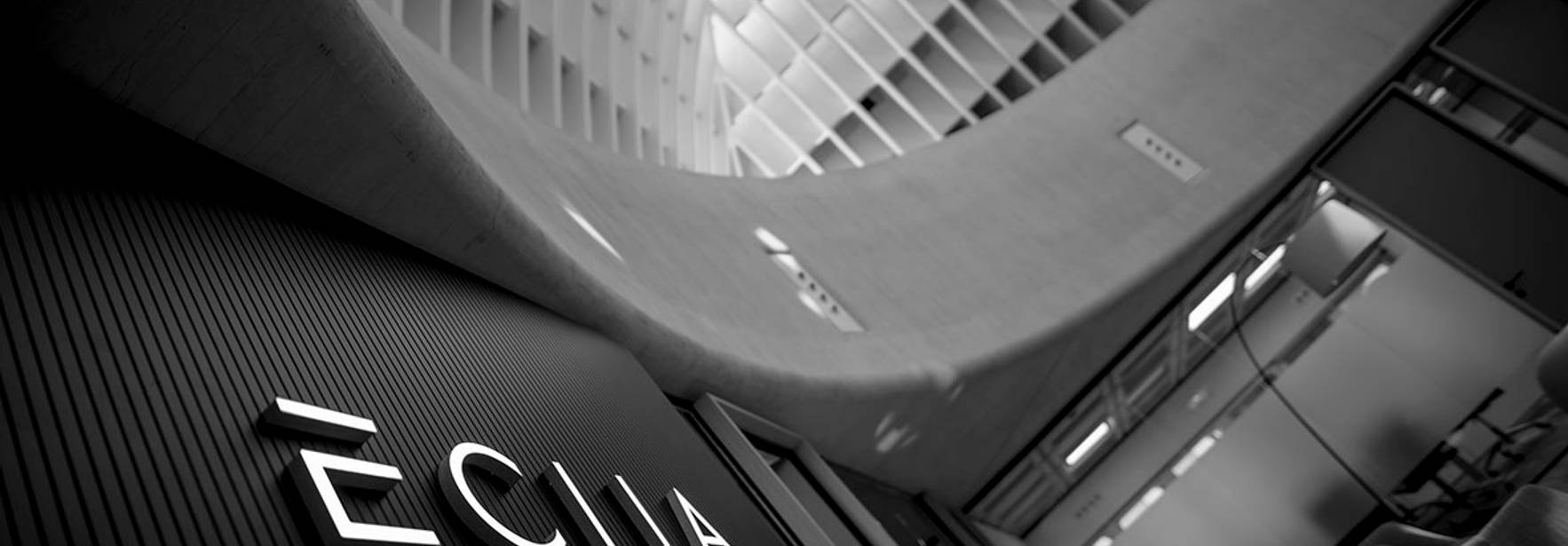 La imagen muestra el logotipo de una empresa en un entorno arquitectónico moderno y minimalista.