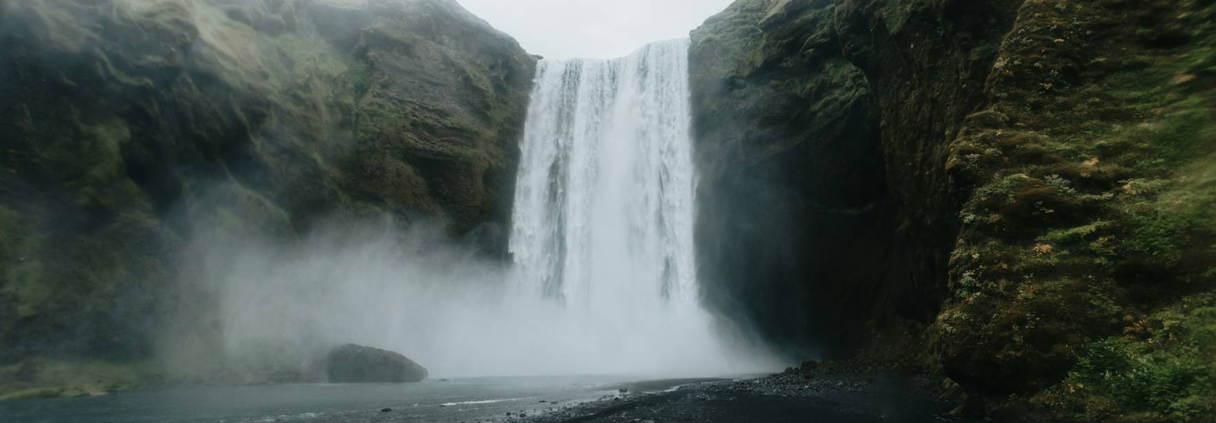 Una majestuosa cascada se despliega entre montañas verdes y un ambiente nebuloso.