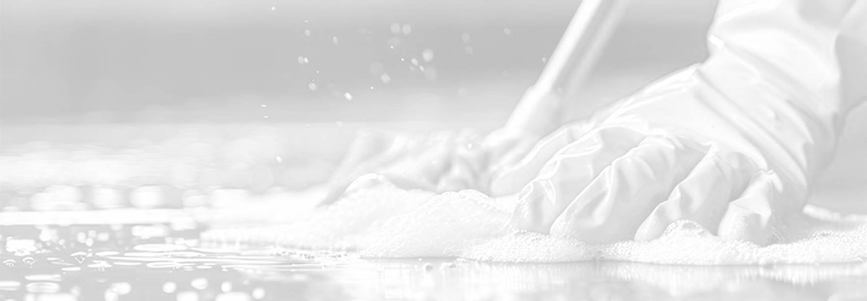 Unas manos con guantes limpian un suelo mojado con detergente.