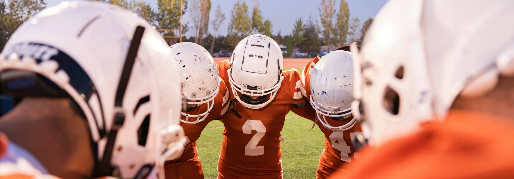 Un grupo de jugadores de fútbol americano se reúne en círculo, preparándose para el juego.