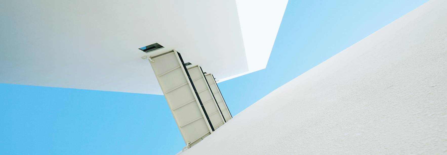 La imagen muestra una estructura arquitectónica moderna con un fondo de cielo azul claro.
