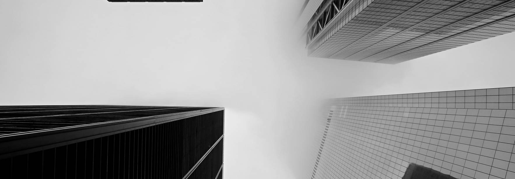 Una vista en ángulo ascendente de edificios modernos en blanco y negro.
