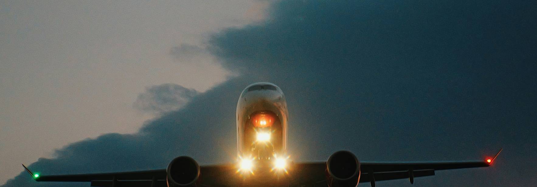 Un avión aterrizando al atardecer, iluminado por sus luces frontales.