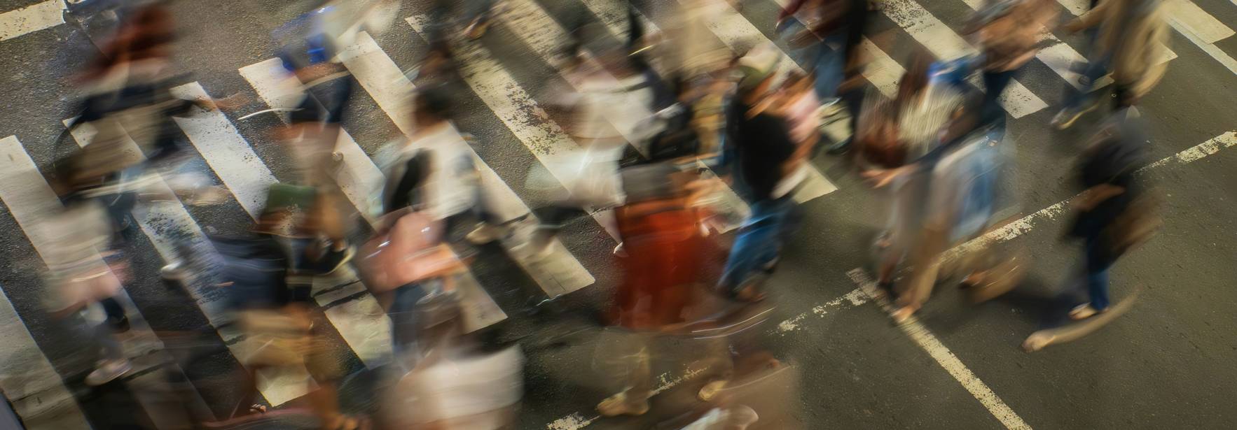 Una multitud de personas cruzando una calle en una intersección de ciudad.