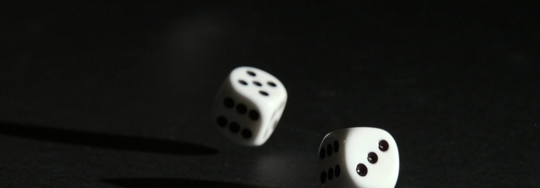Tres dados blancos lanzados en el aire sobre un fondo oscuro.