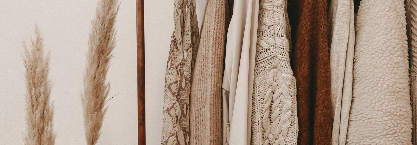 Una variedad de ropa colgada en perchas junto a plantas decorativas.