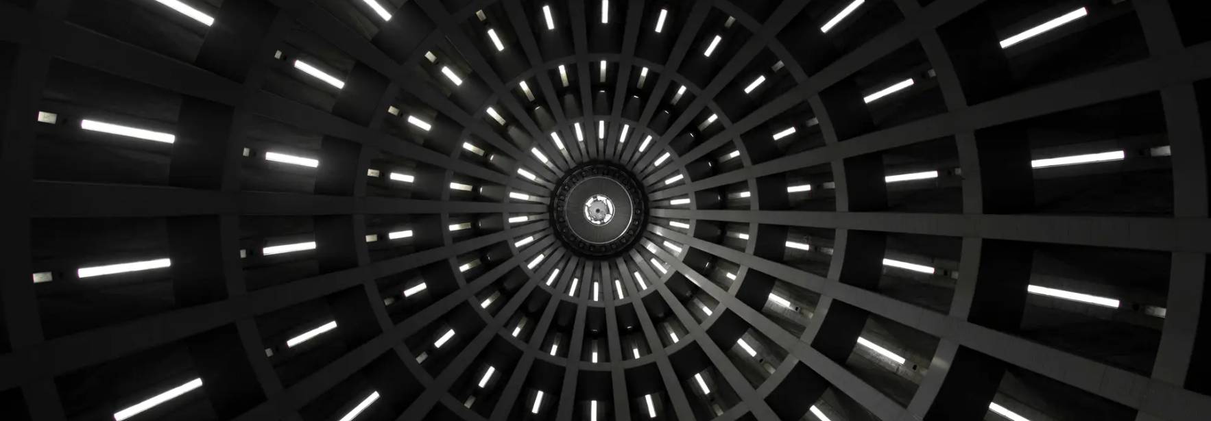 La imagen muestra un patrón circular con luces que emergen de un punto central en un fondo oscuro.