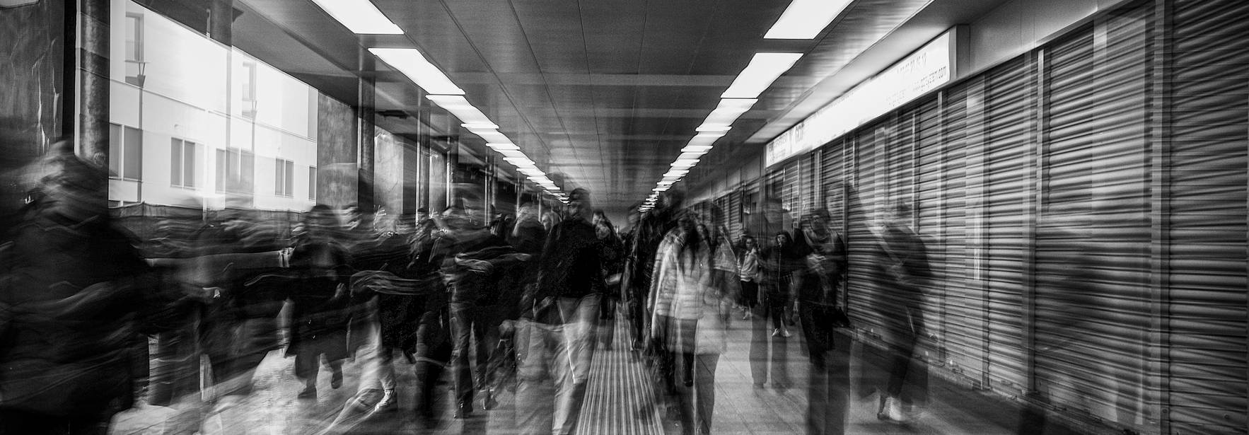 Una multitud de personas se mueve rápidamente por un pasillo urbano difuminado.