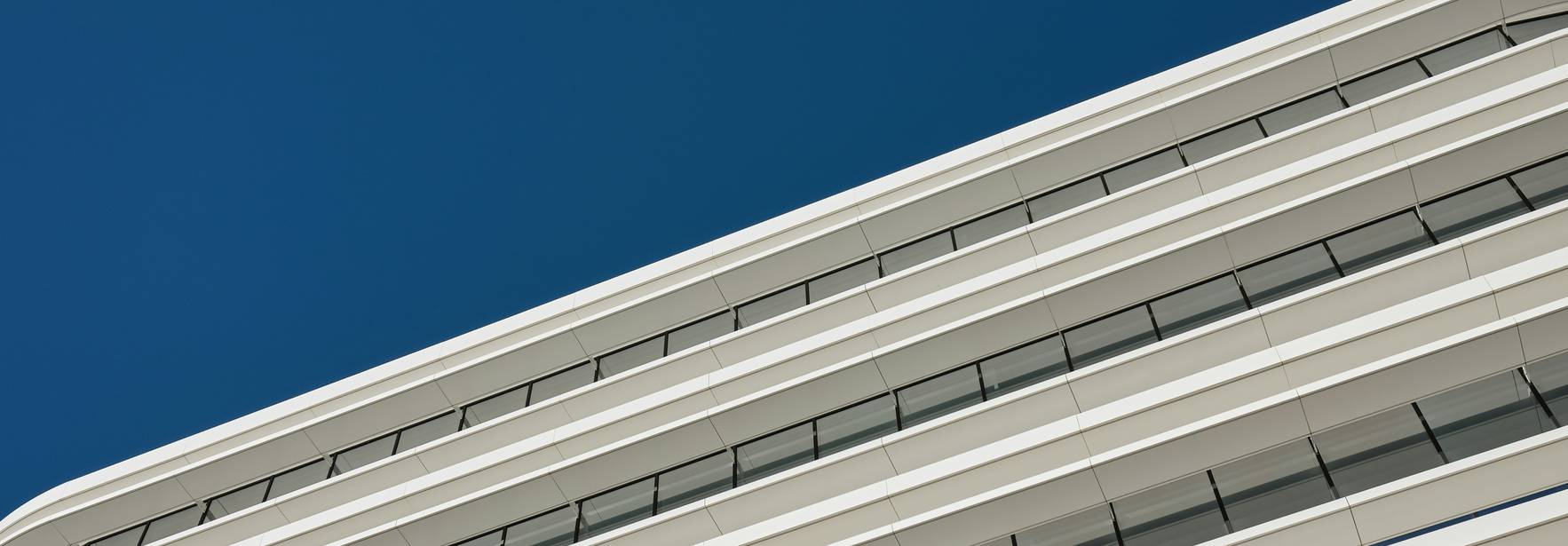 Una fachada moderna de un edificio con ventanas y un cielo azul claro.