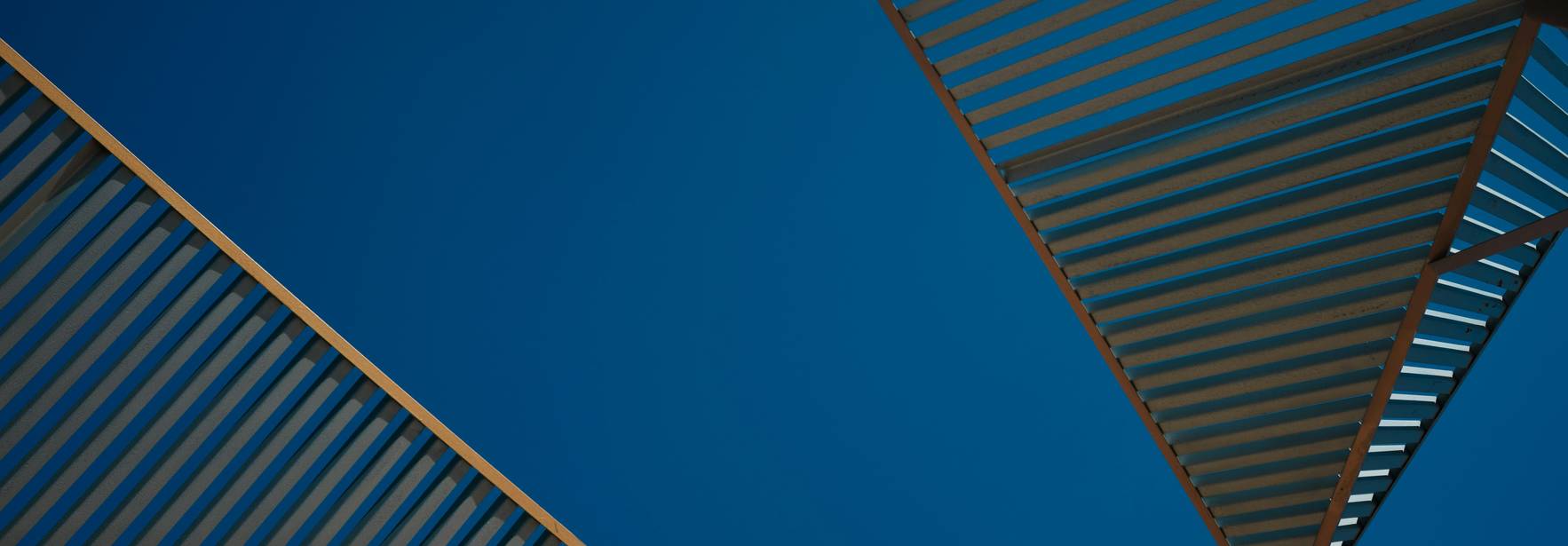 La imagen muestra una perspectiva de estructuras angulares con un fondo de cielo azul claro.