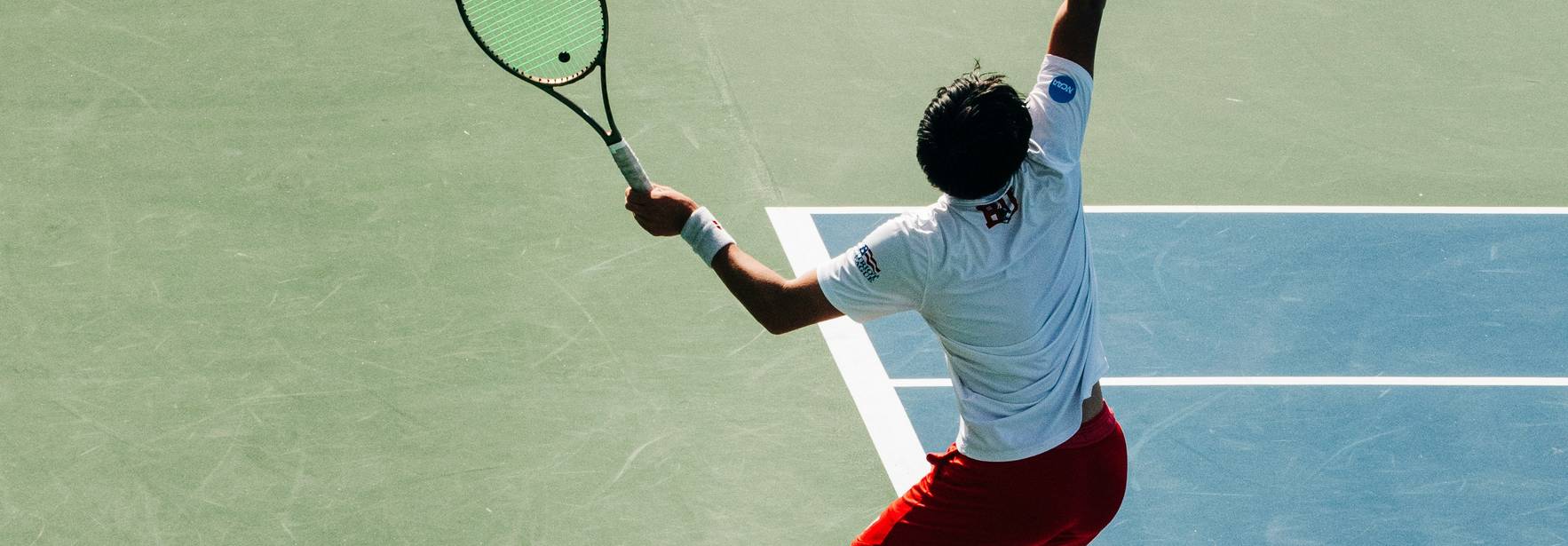 Un jugador de tenis está realizando un servicio en una cancha de tenis.