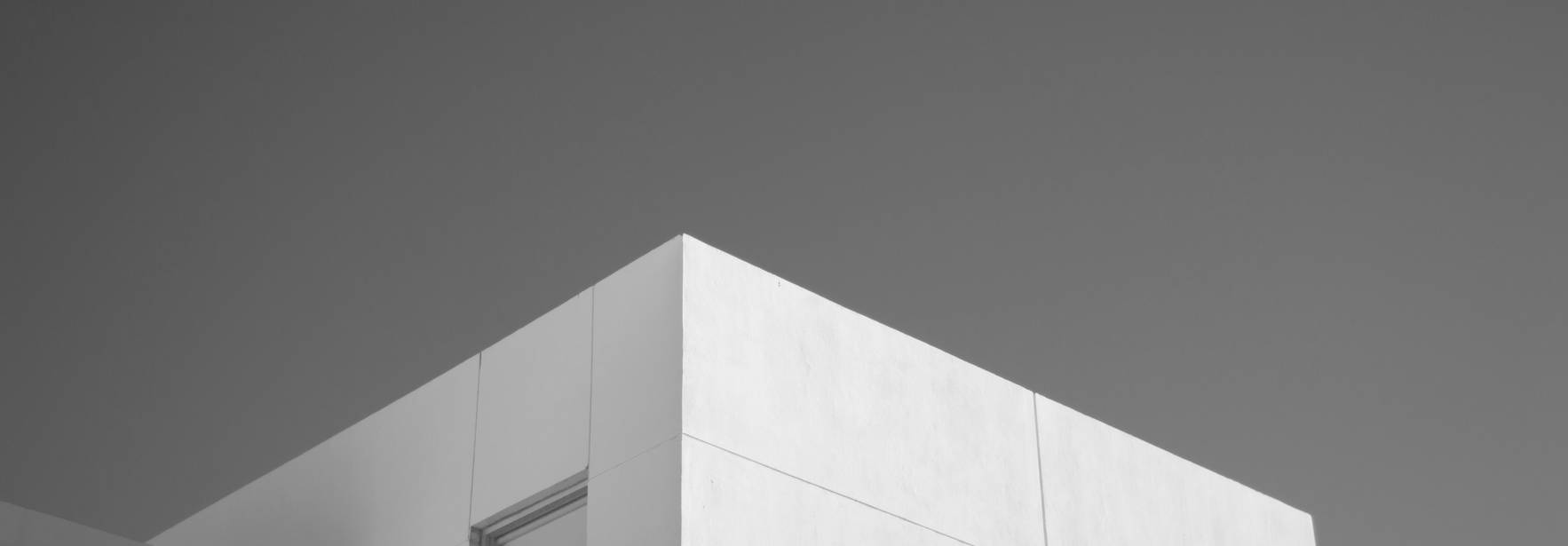 La imagen muestra un edificio moderno de diseño minimalista en blanco y negro.