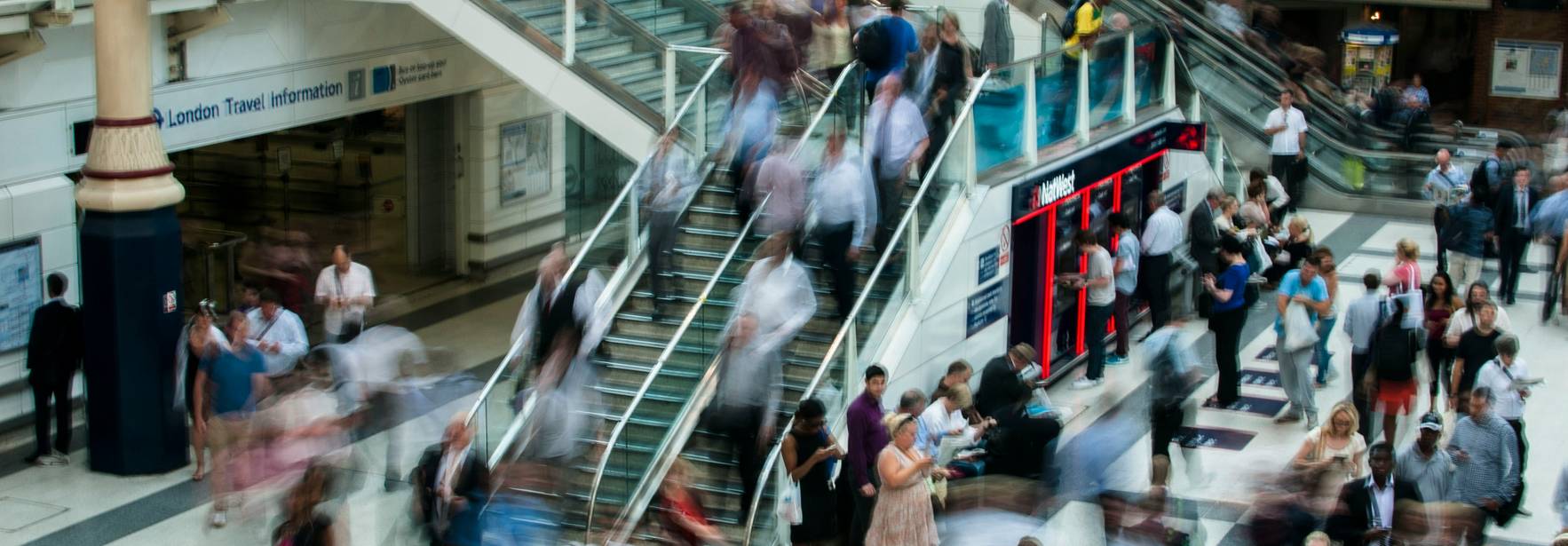 La imagen muestra una estación de transporte público llena de gente en movimiento.