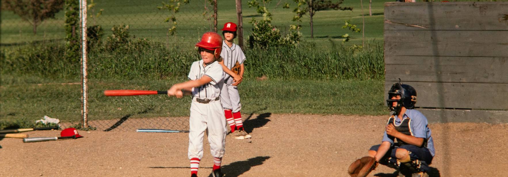 Un grupo de niños juega al béisbol en un campo al aire libre.