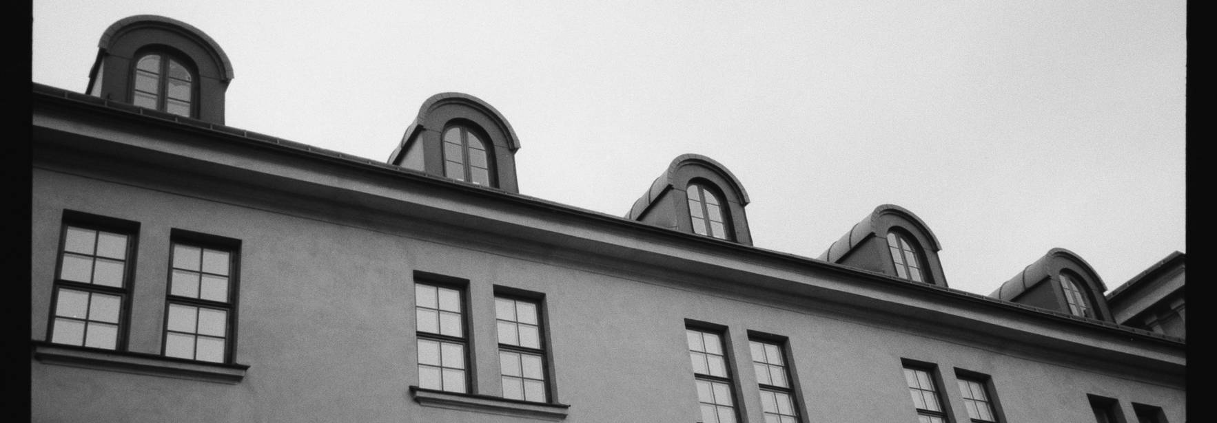 Una imagen en blanco y negro que muestra la parte superior de un edificio con ventanas y techos inclinados.