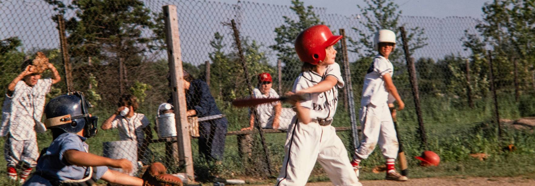 Un grupo de niños juega béisbol en un campo al aire libre.