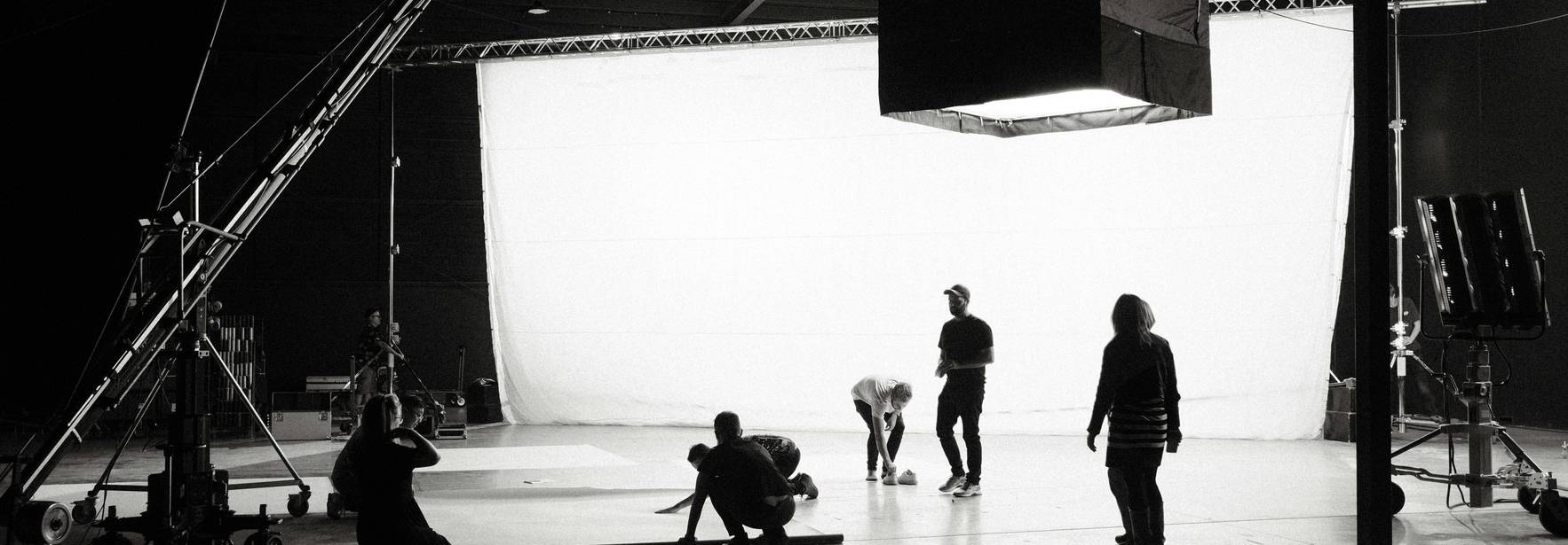 Un grupo de personas trabaja en un set de filmación con un fondo blanco iluminado.