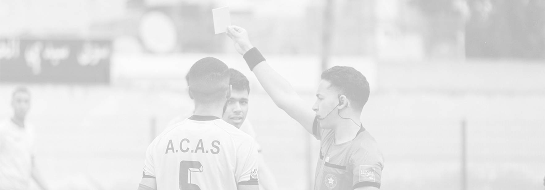 Un árbitro muestra una tarjeta amarilla a un jugador en un partido de fútbol.