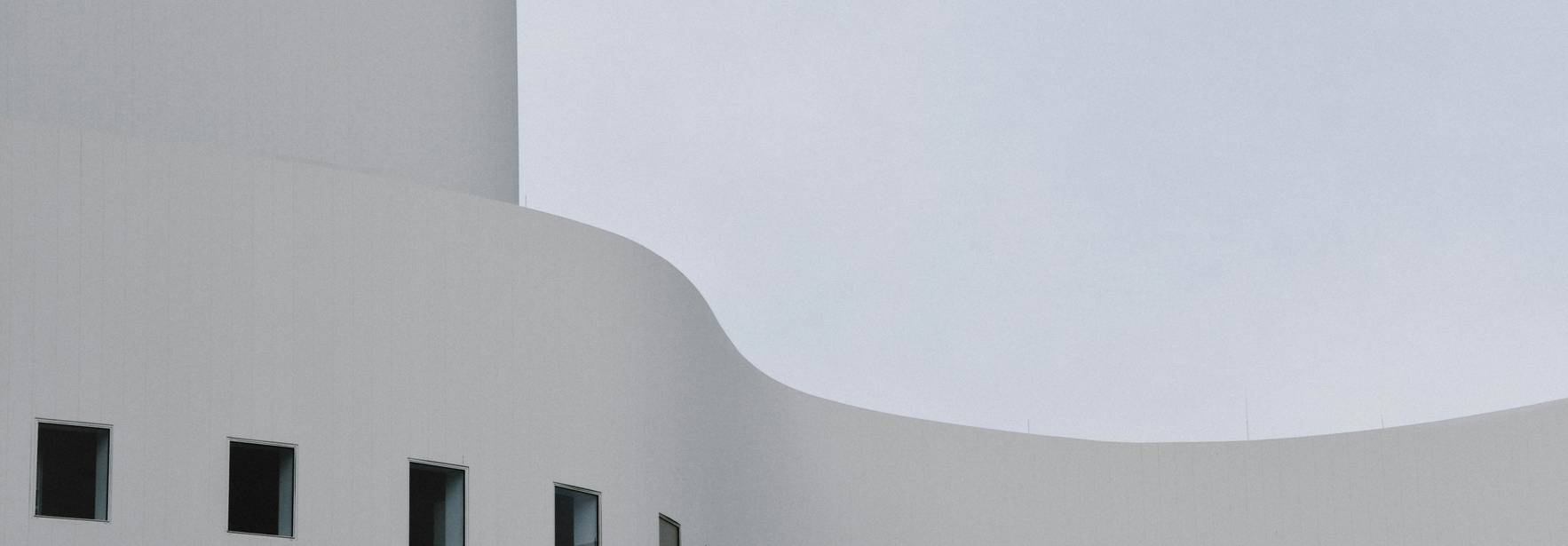 Una fachada moderna de color blanco con ventanas de diseño geométrico.