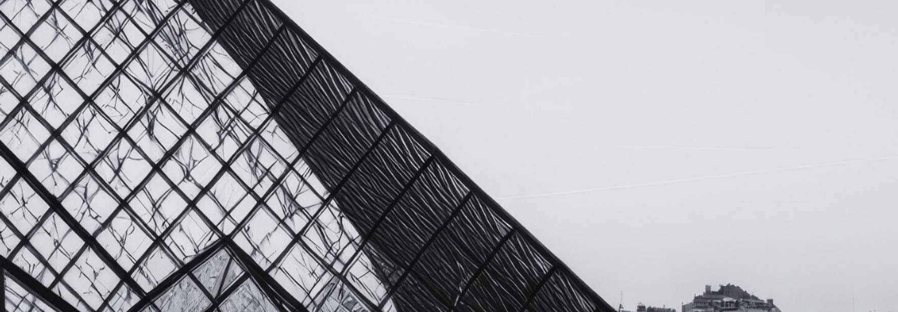 Una estructura moderna de cristal y metal refleja el cielo en el Museo del Louvre de París.