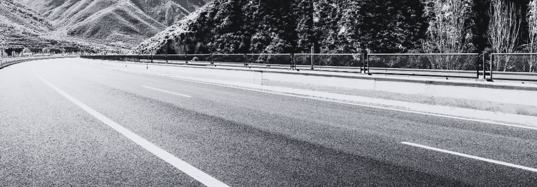 Una carretera serpenteante rodeada de montañas en blanco y negro.