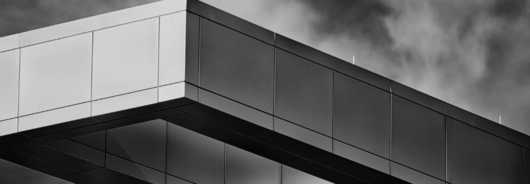 Una estructura arquitectónica moderna en tonos claros, con un diseño geométrico distintivo y un fondo nublado.