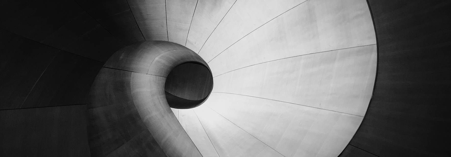La imagen muestra una elegante espiral en tonos de gris que evoca una sensación de modernidad y fluidez.