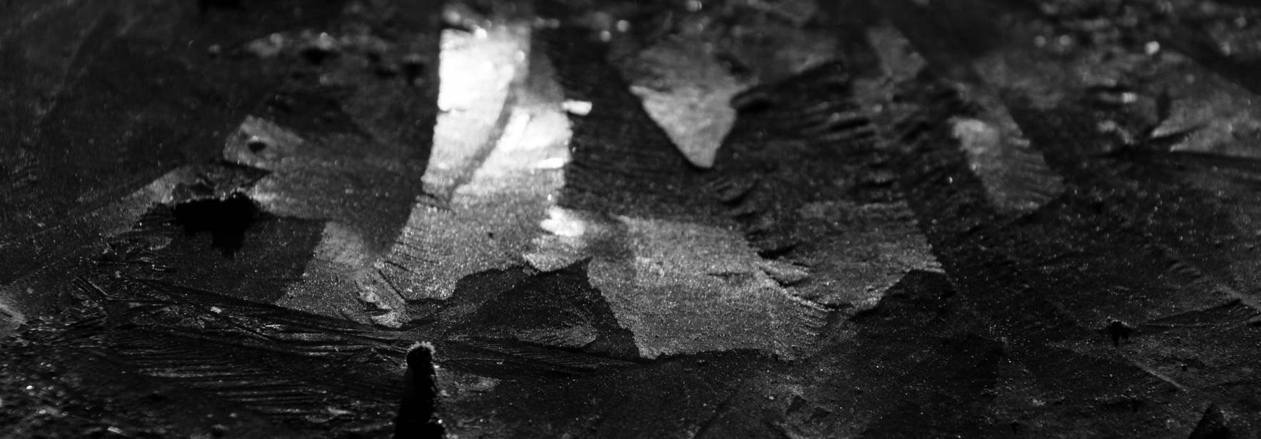 La imagen muestra una superficie oscura con patrones abstractos que parecen ser de hielo o agua en un entorno luminoso.