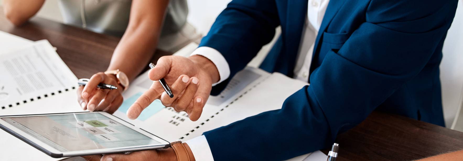 Un grupo de profesionales discutiendo en una reunión mientras utilizan una tablet y toman notas.