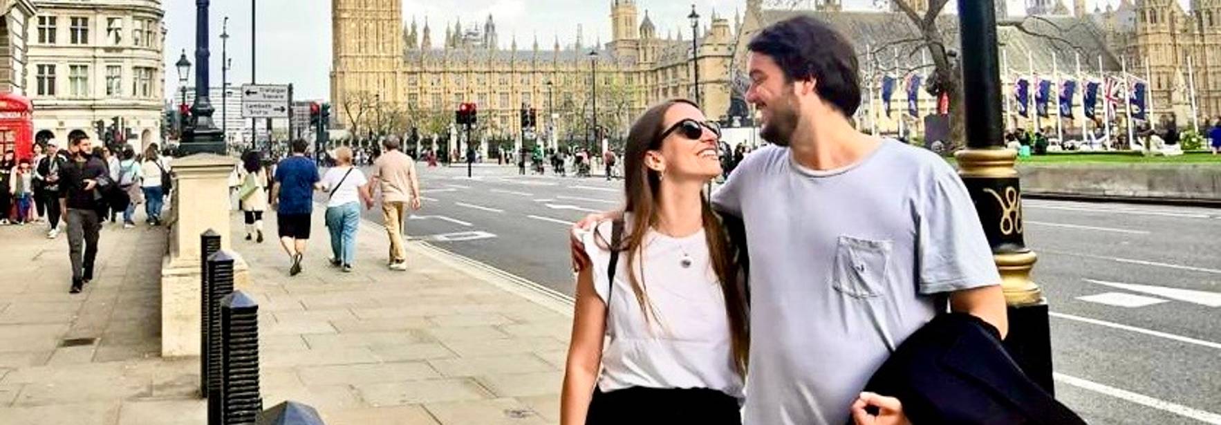 Una pareja sonriente pasea por una calle junto al Big Ben en Londres.