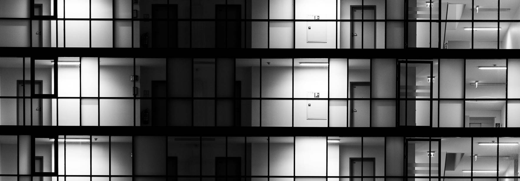 Edificio moderno con fachadas de vidrio iluminadas en un patrón geométrico.