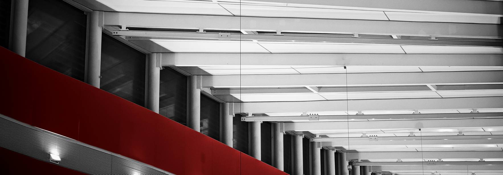 La imagen muestra un interior moderno con techos altos y elementos arquitectónicos en colores blanco y rojo.