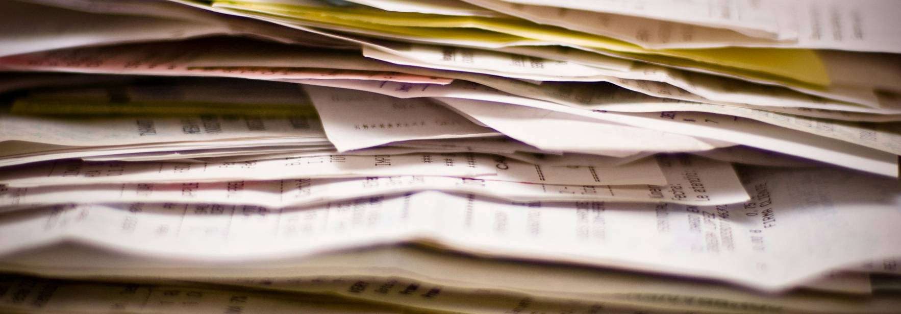 La imagen muestra una gran pila desordenada de papeles y documentos.