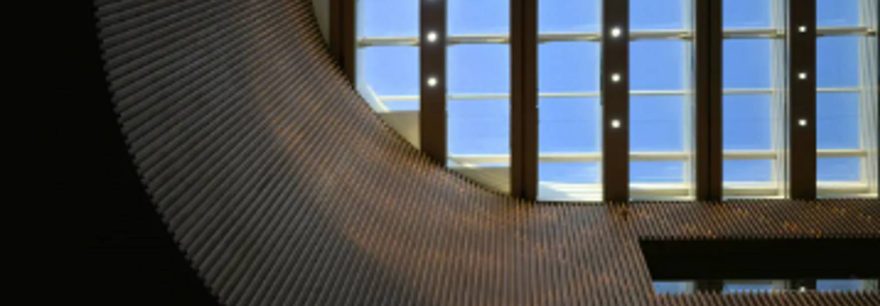 La imagen muestra un diseño arquitectónico con una curva prominente y un cielo visible a través de grandes ventanales.