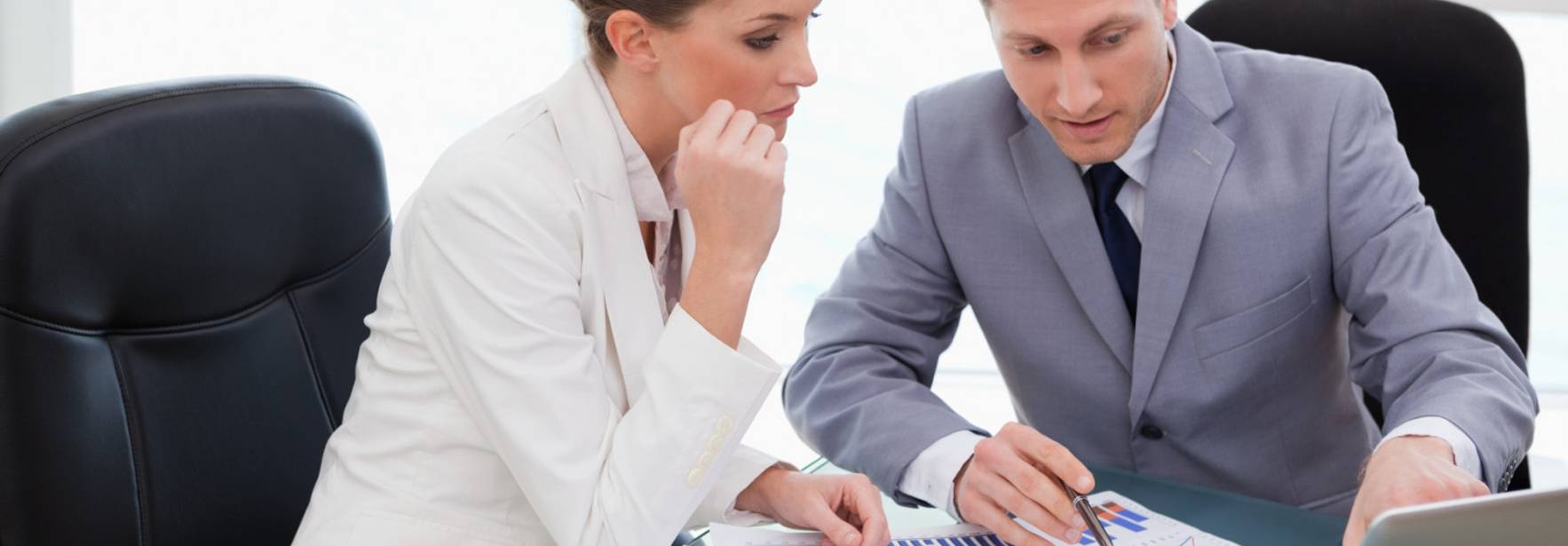 Dos profesionales se reúnen para analizar datos y gráficos en una oficina moderna.