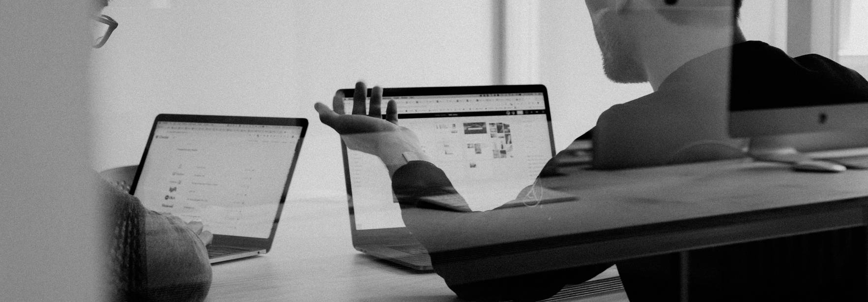 Dos personas trabajando en laptops en una sala de reuniones.