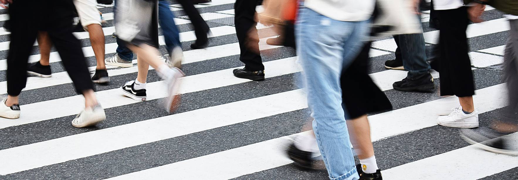 Una multitud de personas cruza una calle en un paso peatonal.