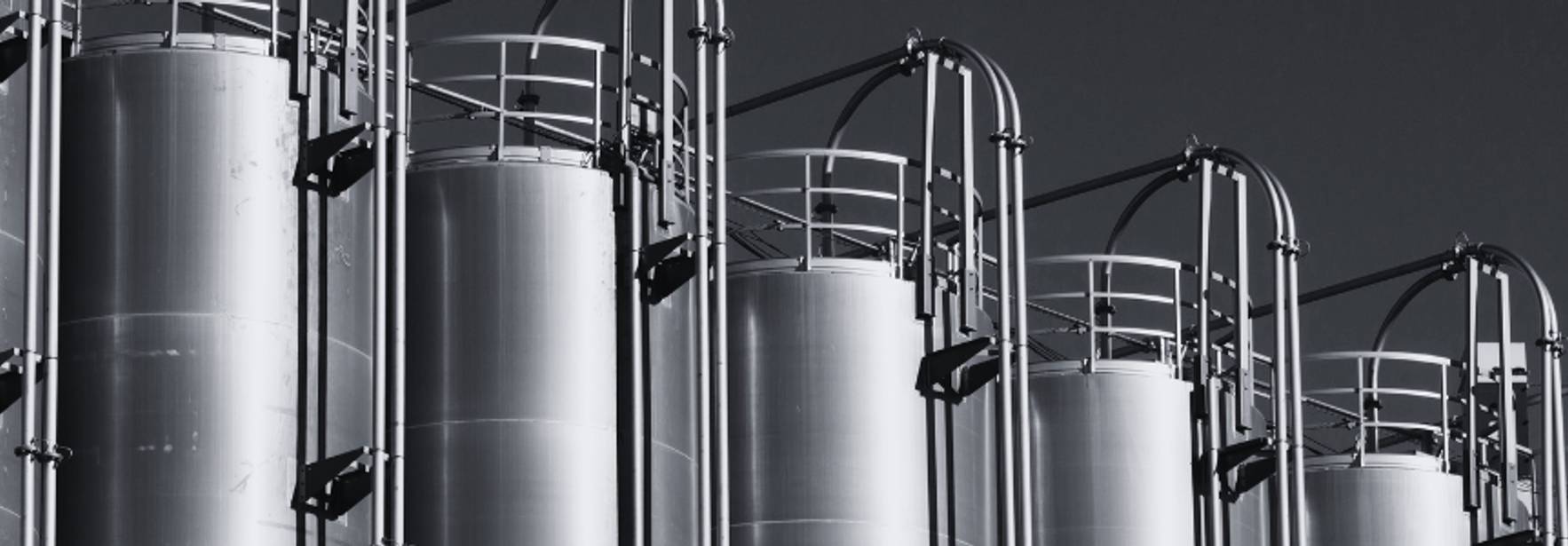 Una serie de grandes tanques metálicos alineados en una imagen en blanco y negro.