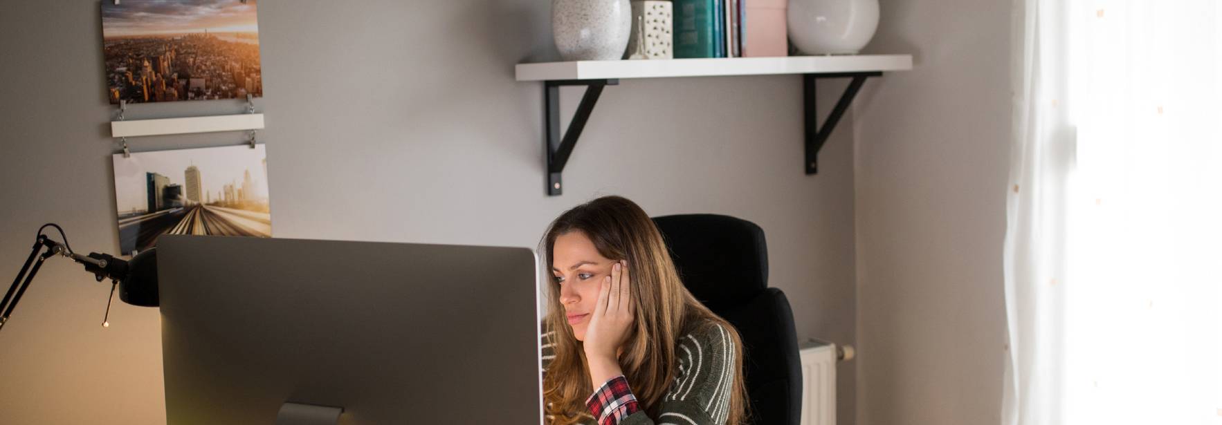 Una mujer trabaja concentrada en su computadora en un ambiente acogedor.