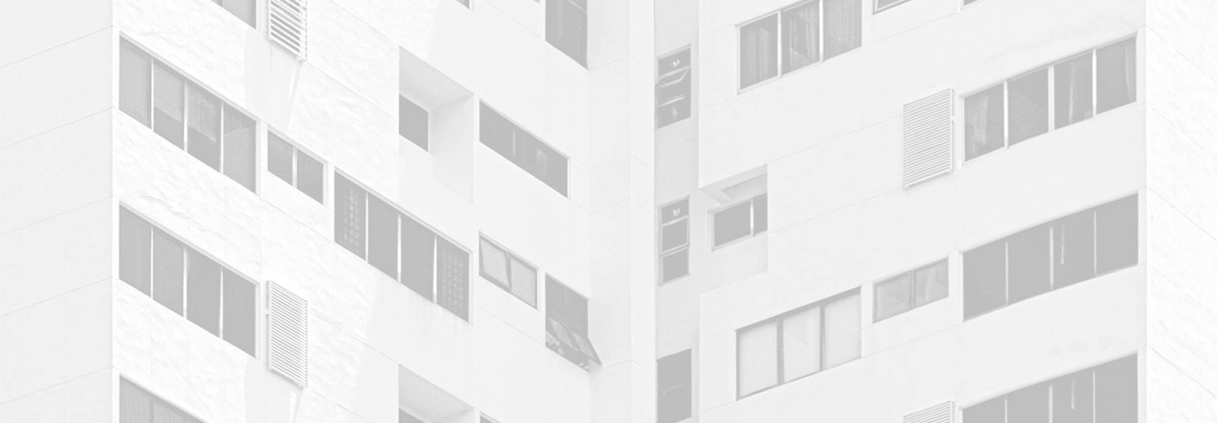 Una imagen que muestra la esquina de un edificio con ventanas en tonos claros.