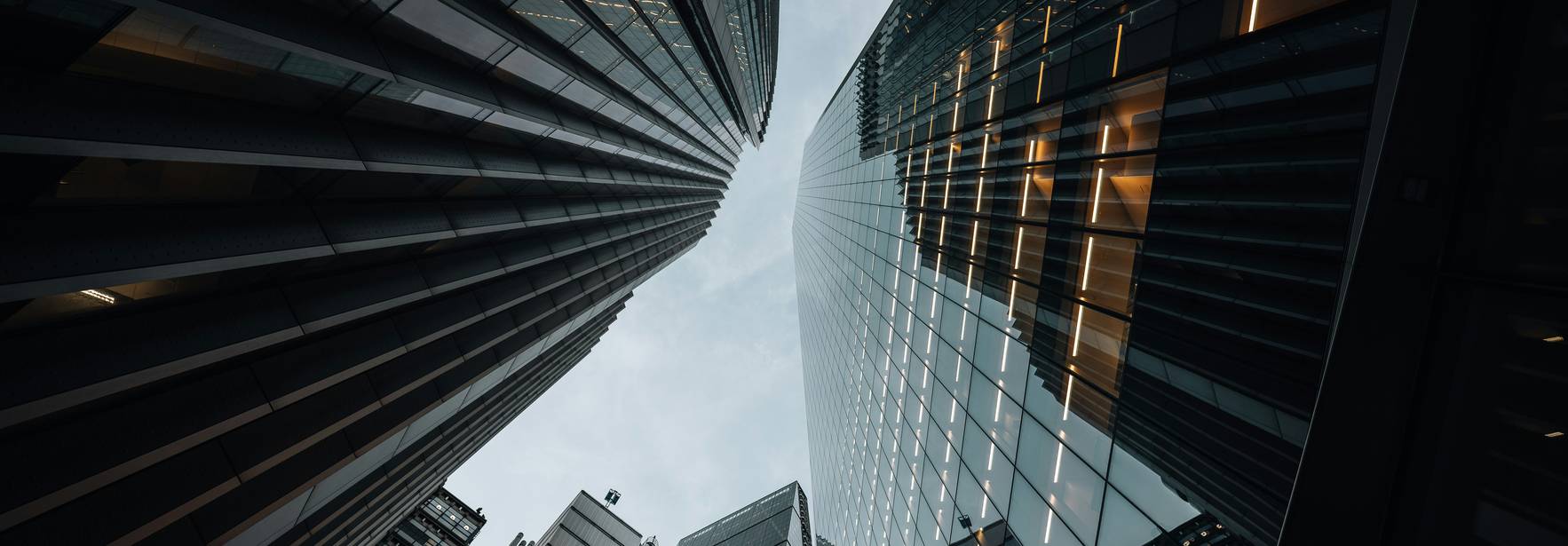 Una vista desde abajo de edificios altos y modernos en una ciudad con un cielo nublado.