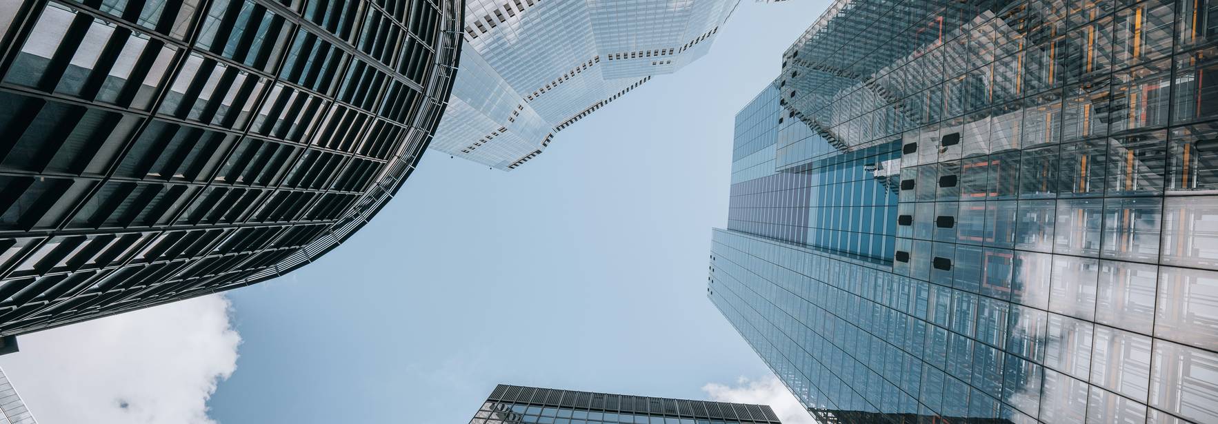 Una vista desde abajo de edificios modernos que reflejan el cielo.