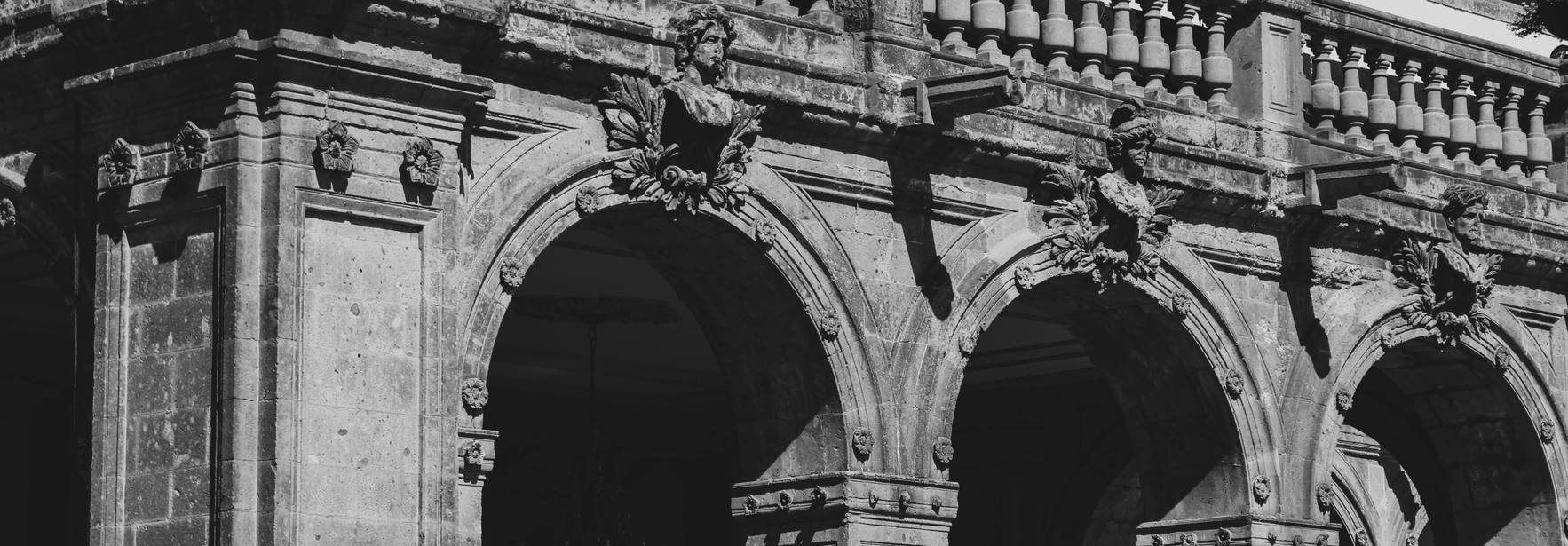 Mexico La imagen muestra la fachada de un antiguo edificio con arcos y adornos arquitectónicos en blanco y negro.